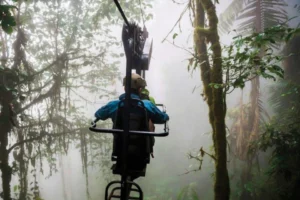 Adventurous traveler on a skybike gliding through the misty treetops at Mashpi Lodge, Ecuador's cloud forest sanctuary.