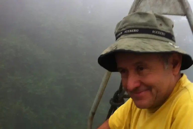 Fernando Timpe in a yellow shirt and bucket hat, enjoying the misty atmosphere of a high-altitude forest adventure.