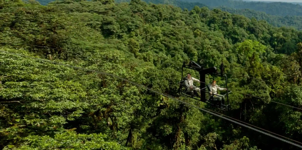 Adventurous guests enjoying Mashpi Lodge's sky bike, gliding above the lush Ecuadorian cloud forest canopy for a unique perspective.