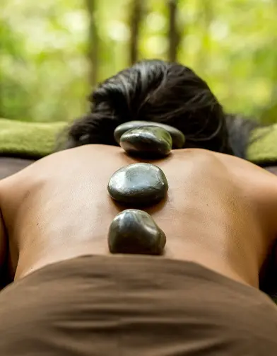mashpi lodge relajar spa piedras calientes Tranquil hot stone therapy at Mashpi Lodge spa amidst the serene forest backdrop.