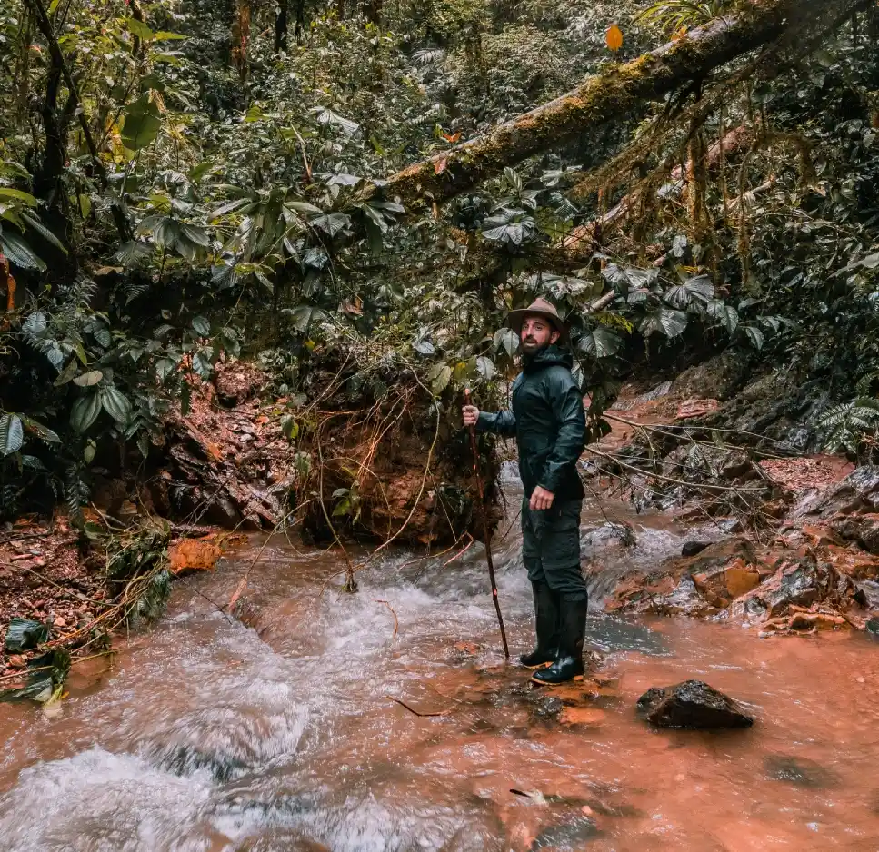 Un aventurero excursionista explorando los vibrantes senderos empapados de agua de la Reserva Mashpi en Ecuador.